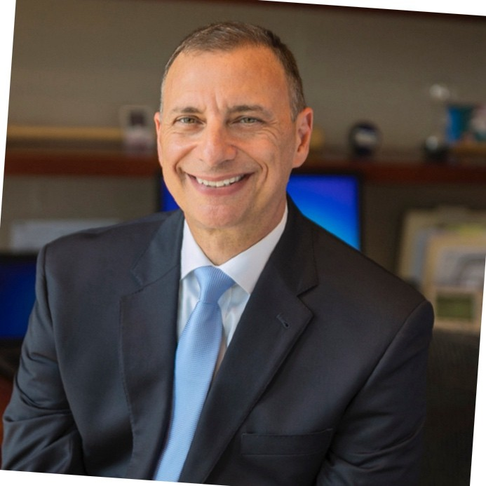 Brian_Fishel seen smiling for a photo in a white color shirt and black color suit